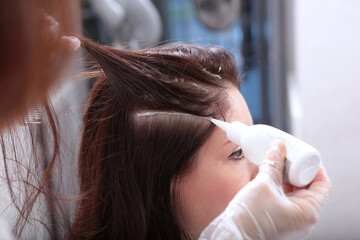Hairdresser in beauty salon doing spa treatments for hair. Application of nourishing agents for hair growth and strengthening. Hair and scalp care in a beauty salon.