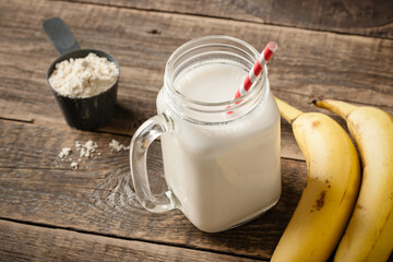 Whey protein cocktail and banana fruit on wooden table - 432408031