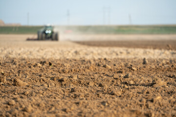 agricultural machinery works in the field. A tractor with a plow cultivates the land before sowing wheat and other cereals. Soft focus, plowed ground close-up. Empty space for inserting text