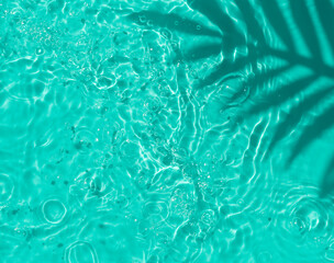 Blue water texture background on the noon sunlight with tropical leaves shadow.	