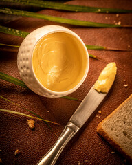 Butter placed in a little white container with a butter knife and a bread ready for breakfast
