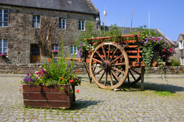 Fototapeta na wymiar Brittany, France. Wooden carriage decorated with flowers at the square of the medieval village Locronan.