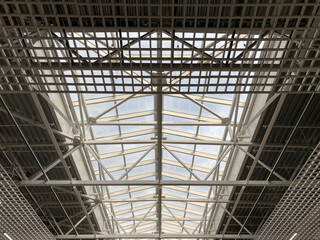 Roof metal trusses in the shopping center. Sky, lines, transparent roof, perspective