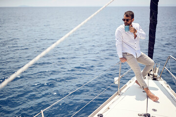 A young handsome barefoot male model is enjoying the view at a photo shooting on a yacht on the...