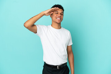 Young African American man isolated on blue background saluting with hand with happy expression © luismolinero