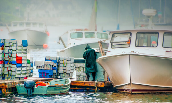 Foggy cold morning. Commercial Fisherman in a hooded slicker  makes ready to spend the day at sea.