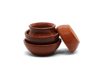 A set of earthenware (ceramic) dishes. Three earthenware bowls of different sizes and a pot, handcrafted in a pottery workshop and covered with glaze. Isolated on white.