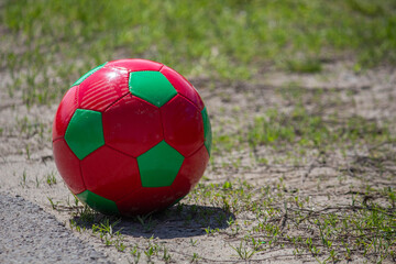 Fototapeta na wymiar A red-green soccer ball stands on the ground 