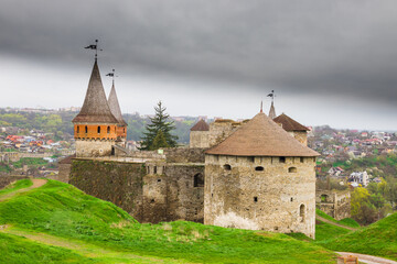 Fototapeta na wymiar Old Kamianets-Podilskyi Castle under a cloudy grey sky. The fortress located among the picturesque nature in the historic city of Kamianets-Podilskyi, Ukraine