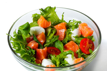 Healthy food concept. Fresh salad with salmon, arugula, cherry tomatoes and lettuce isolated on white. transparent dishes with food. Advertising poster. Close-up view.