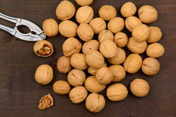 lots of walnuts and nutcracker close up on wood background