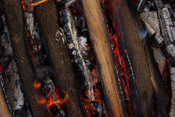 Old wooden boards are engulfed in flames in the grill