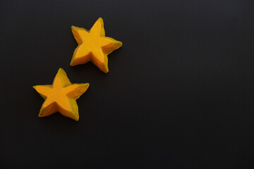 Two yellow star candles on black background