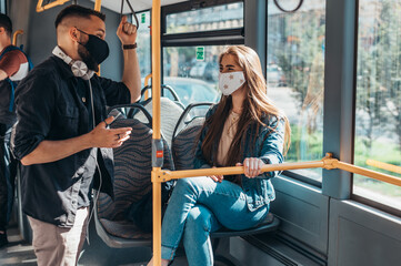 A couple of friend meeting in a bus while wearing a protective mask