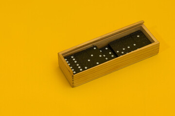 dominoes in a wooden box on a yellow background