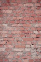 Red brick wall with cracks and breaks. Old brickwork with traces of restoration and grouting with cement.