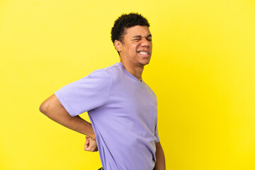 Young African American man isolated on yellow background suffering from backache for having made an effort