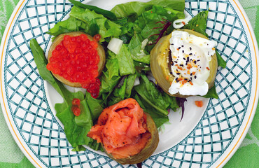 Dish of artichoke bottom topped with smoked salmon, salmon roe and poached eggs over greens