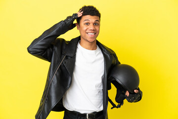 Young African American man with a motorcycle helmet isolated on yellow background with surprise...
