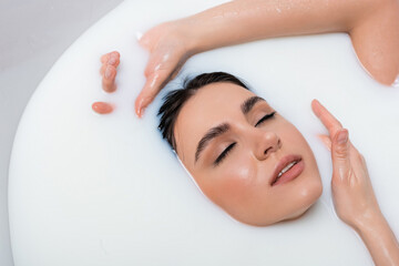 pretty woman with closed eyes relaxing in milk bath.