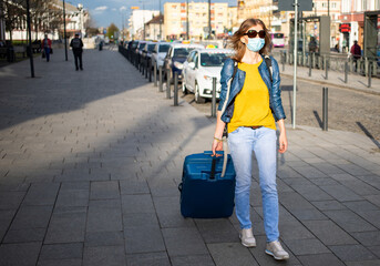 woman traveler with suitcase wearing mask