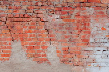 Red brick wall with cracks and breaks. Old brickwork with traces of restoration and grouting with cement.