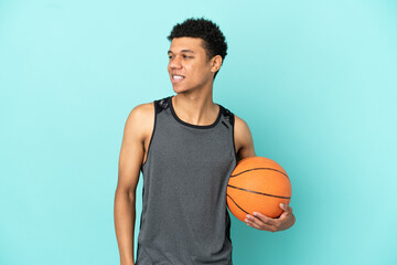 Basketball player African American man isolated on blue background looking to the side and smiling