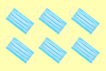 medical surgical blue masks on yellow background isolated. pandemic and pollution concept