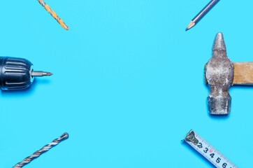 screwdriver, tape measure, hammer, pencil and drill on a blue background. copy space. renovation concept