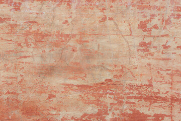 A red-yellow fragment of a concrete wall with a copious amount of scratches. Rough surface with scuffs and cracks.