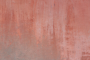 A pink-yellow fragment of a concrete wall with a copious amount of scratches. Rough surface with scuffs and cracks.