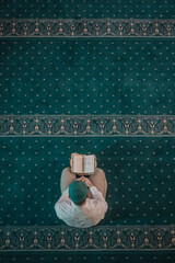 Muslim man praying in mosque and reading Quran