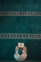 Muslim man praying in mosque and reading Quran