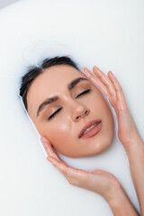 Naklejka premium sensual woman touching face while relaxing in bath with milk.