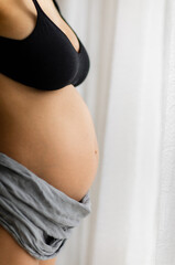 Pregnant woman belly near the windows. Pregnancy and motherhood  concept.