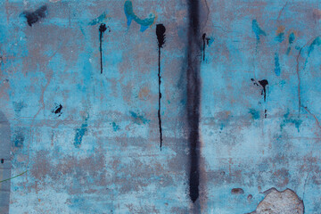 Grey concrete wall with natural defects. Fragment of the cement surface with natural texture. Elements of blue paint on a dark wall.