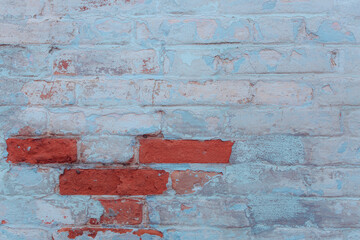 Old ragged wall with peeling blue plaster. Natural damage to dilapidated bricks. Natural environment concept.