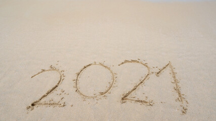 Happy New Year 2021 Text on the beach, 2021 year message hand written in sand on beautiful beach Copy space on sandy beach background. New Years concept