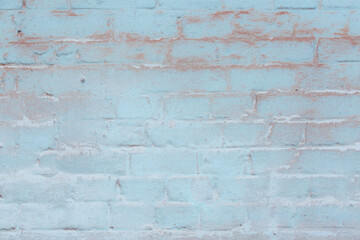 Old ragged wall with peeling blue plaster. Natural damage to dilapidated bricks. Natural environment concept.