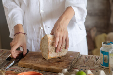  cuts light homemade bread on antique style. hands with a knife and bread