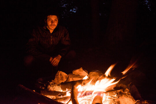A man 30-40 years old sits around a campfire at night