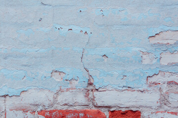 Old ragged wall with peeling blue plaster. Natural damage to dilapidated bricks. Natural environment concept.