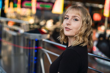 Retrato cercano de chica rubia guapa en zona de atracciones de una feria