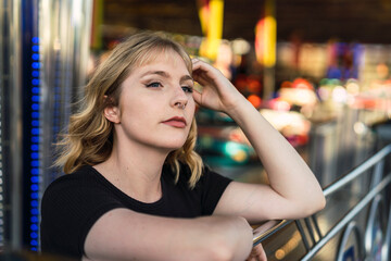 Chica guapa rubia posando frente a atracciones de feria