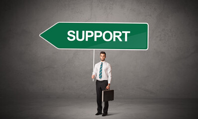 Young business person in casual holding road sign