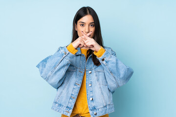 Young caucasian woman isolated on blue background showing a sign of silence gesture