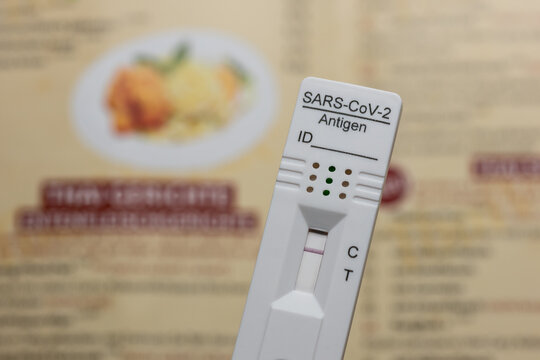 Testing Before Going To A Restaurant: Rapid Antigen Corona Test Showing A Negative Result In Front of A Menu