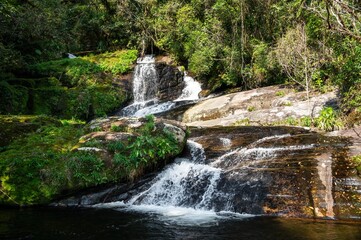 Ipiranguinha waterfall with his water current flowing around rock formations and creating a golden natural pool right below in the dense Serra do Mar (Sea Ridge) forest in Cunha, Sao Paulo - Brazil.