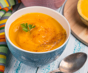 Traditional autumn pumpkin soup-puree on a blue background.