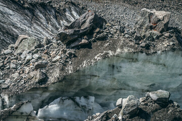 Nature background with icefall near glacier wall with cracks and scratches. Natural backdrop with icy wall and blocks of ice. Beautiful landscape with shiny glacial wall and ice blocks in sunlight.